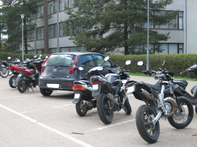 Car and mopeds parked in parking lot.