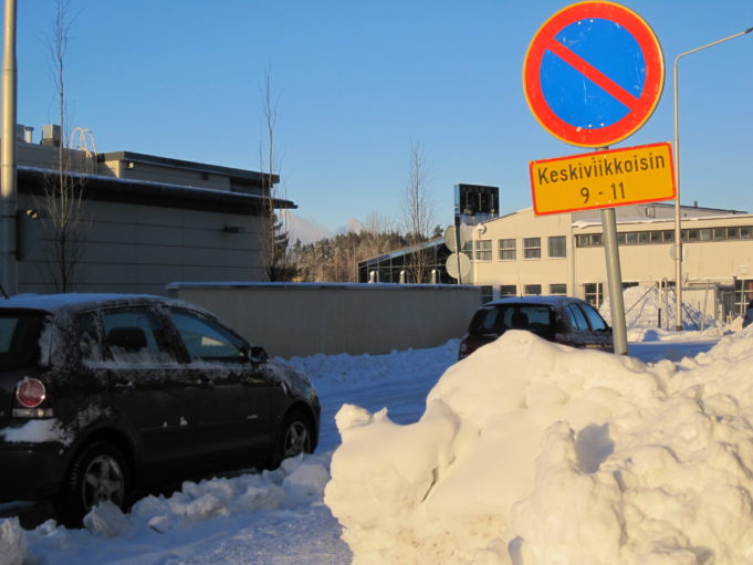 Car parked in winter conditions. Traffic sign explains winter parking restrictions.