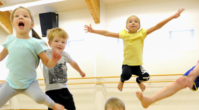 Lapsijoukko hyppää ilmaan liikuntasalissa