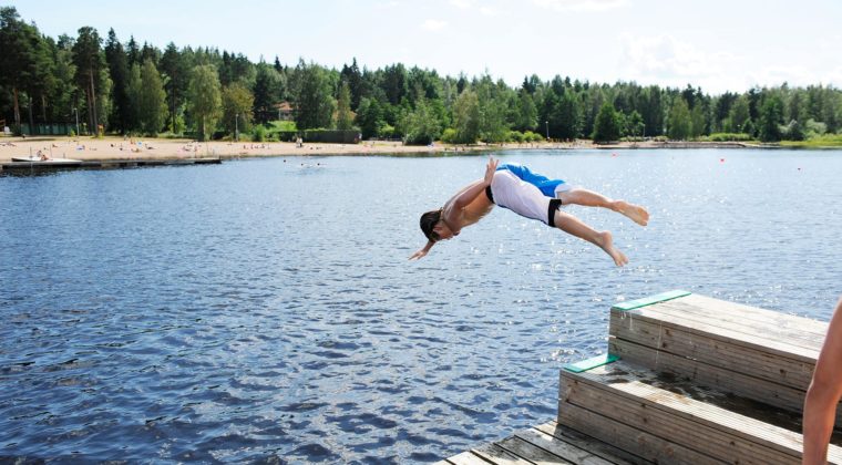 Poika hyppää laiturilta Käyrälampeen