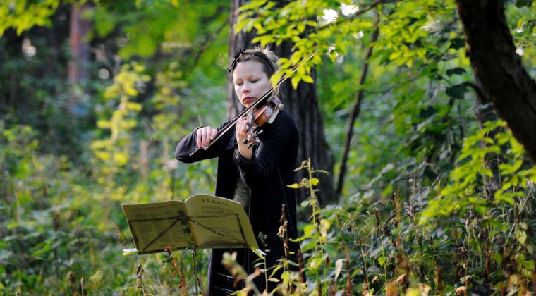 tyttö soittaa viulua puiden siimeksessä