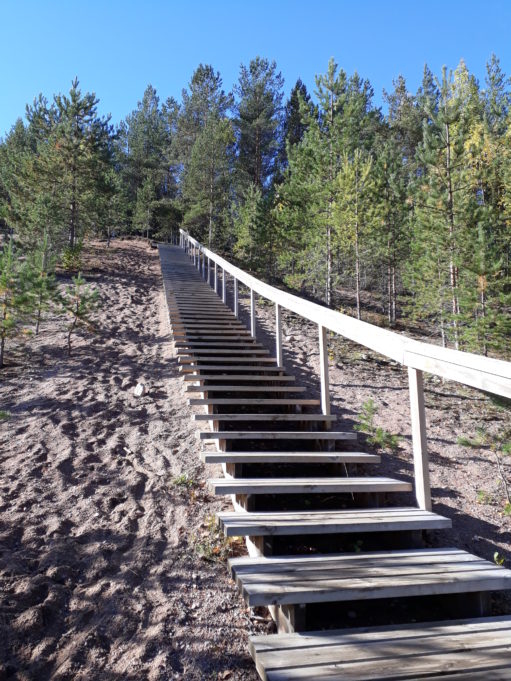 Hiekkaharju jossa puiset portaat. Portaissa kaide ylösmennessä oikealla puolella.