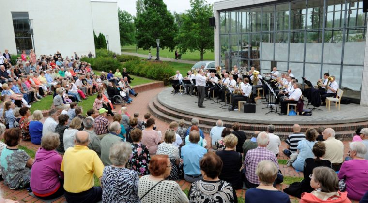 Ihmisiä kuuntelemassa musiikkiesitystä Kuusankoskitalon ulkonäyttämöllä