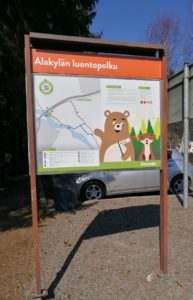 Luontopolun opastalu, jossa teksti Alakylän luontopolku. Taulussa piirroshahmoina karhu ja kettu metsässä.