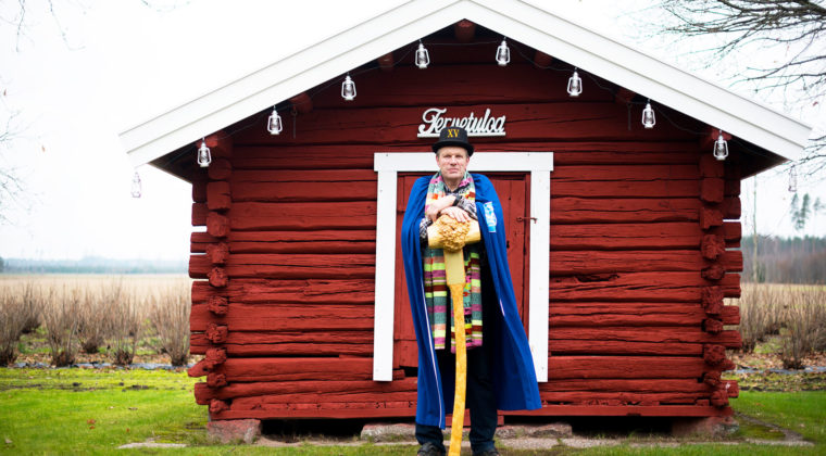 Jukka Naukkarinen punaisen hirsimökin edustalla