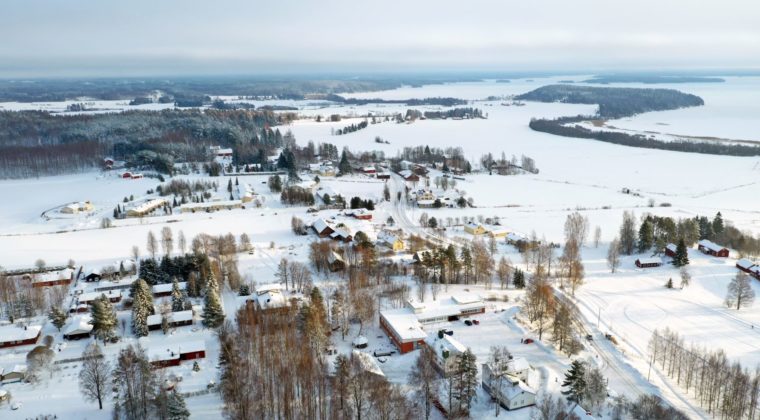 Ilmakuva lumisesta Jaalan kirkonkylästä. Kylän läpi kulkee tie pohjois-eteläsuunnassa. Lumikattoisia rakennuksia on tien länsipuolella. Etäämmällä näkyy lumisia peltoaukeita ja järvenselkää.