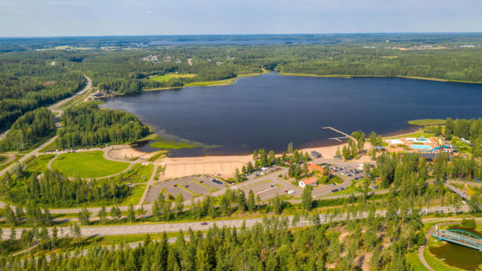 Ilmakuva, Käyrälampi kesällä. Vesipuisto, uimaranta, parkkipaikat, metsää ja teitä ympärillä.