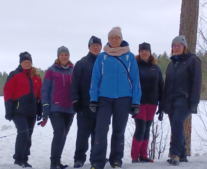 Ryhmä poseeraa kameralle talvisessa maisemassa. Viisi naista ja yksi mies.