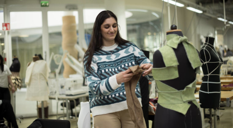 Henkilö mallaa vaatetta ompelunuken päälle.