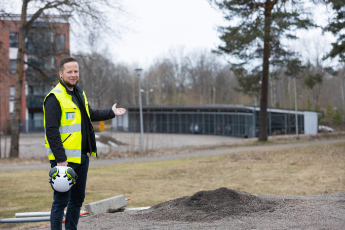 Mies huomioliivissä osoittaa tyhjän tontin suuntaan Kouvolan Halkotorilla