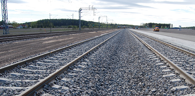 Terminaaliraiteet, joiden oikealla puolella näkyy katujyrä tasaamassa sorapintaista kenttää, ja vasemmalla huoltotie.