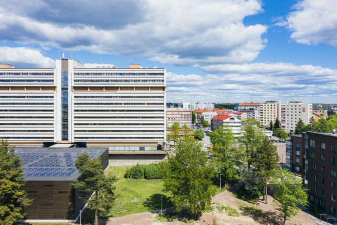 Pohjolatalo, puita, sininen taivas ja poutapilviä