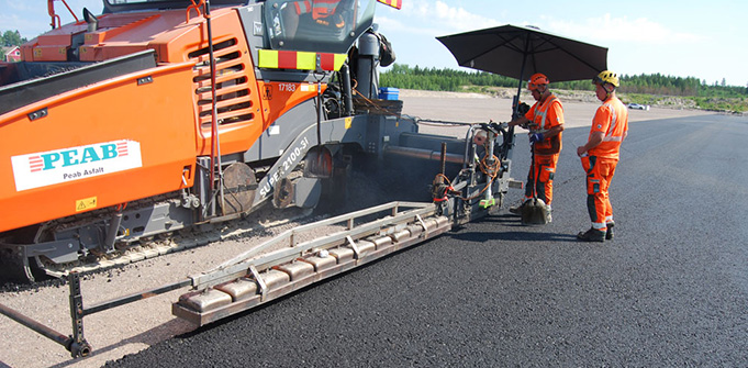 Asfalttikone ja työntekijöitä tekemässä uutta asfalttipintaa.