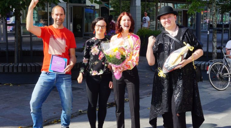 Neljä iloista ihmistä palkintojen kera kävelykatu Manskilla