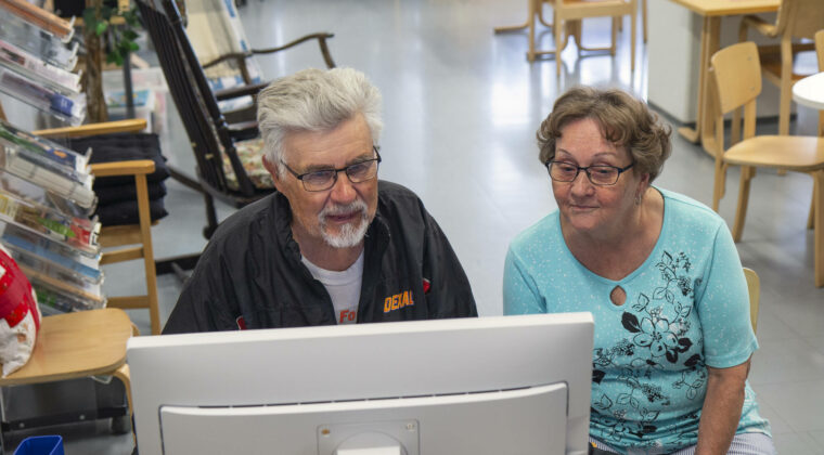 Seniorit tutkailevat yhdessä tietokoneen ruutua.