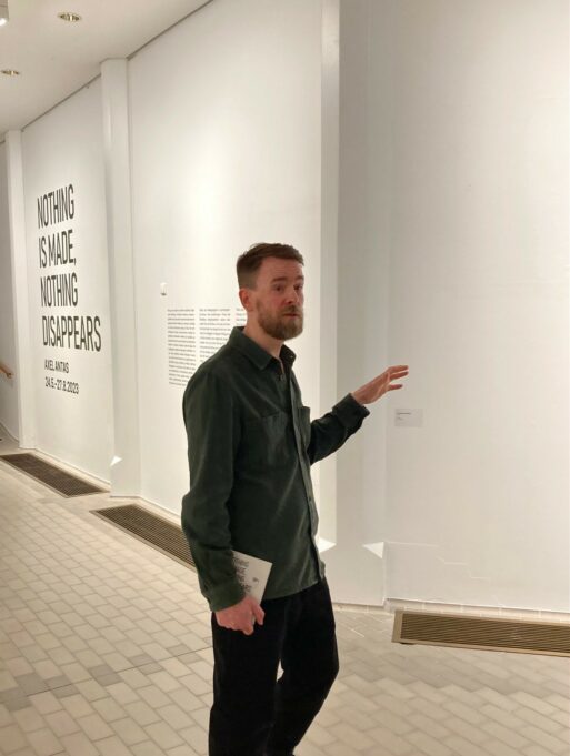 Axel Antas taidemuseossa ketomassa omista teoksistaan. Taustalla näkyy näyttelyn nimi museon seinällä.