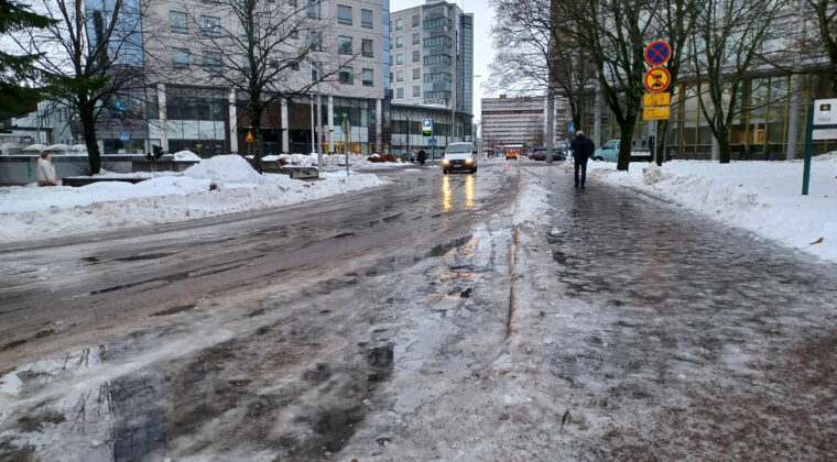 Kaupunkinäkymä, jäinen, hiekoitettu katu, kerrostaloja.