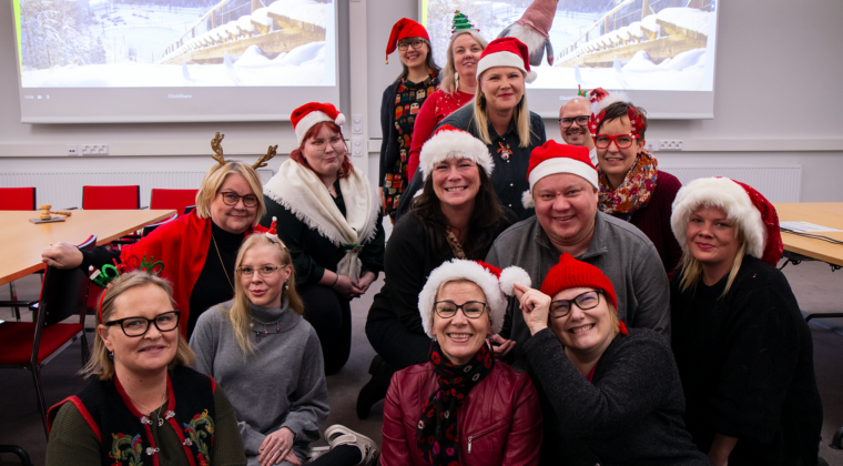 Iloisia henkilöitä ryhmäkuvassa tonttulakit päässä