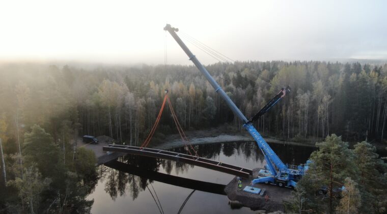 Nosturi nostaa Käyrälammen ulkoilureitin siltarakennetta paikalleen Käyräjoella