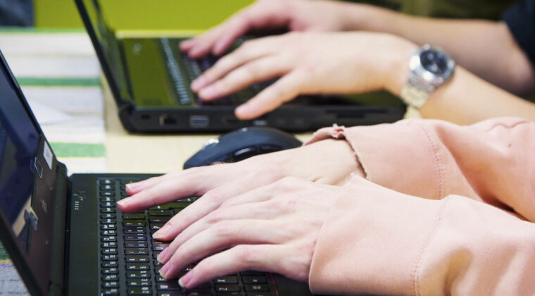 Kaksi henkilöä kirjoittaa läppäreillä.