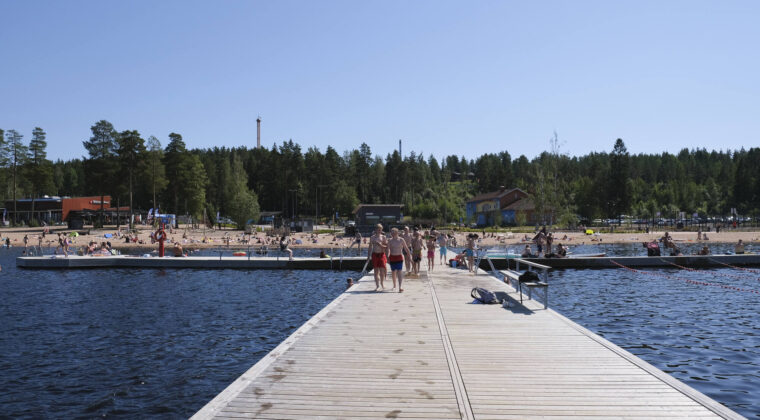 Laituri ja uimaranta aurinkoisena päivänä. Paljon ihmisiä.