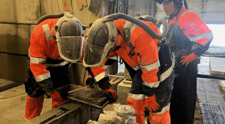 Haalaripukuiset työntekijät mittaavat graniittia Kymen Graniten tiloissa.