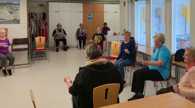 Ryhmä nauravia naisia tuolijumppaamassa