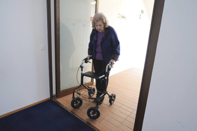 Nainen kulkee rollaattorin kanssa ovella kohti kynnystä.