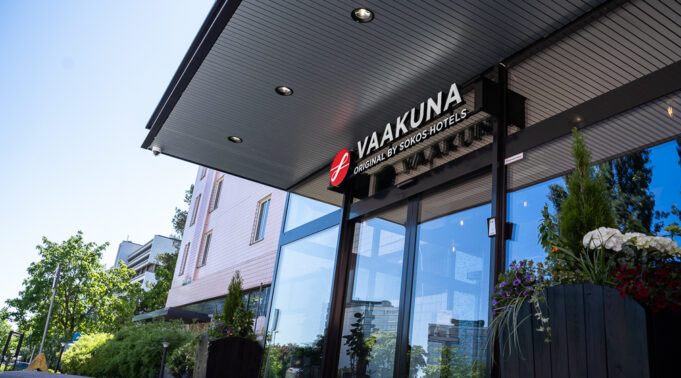 Glass-doored entrance of a pink building. Above the door, a sign reads “Vaakuna.”