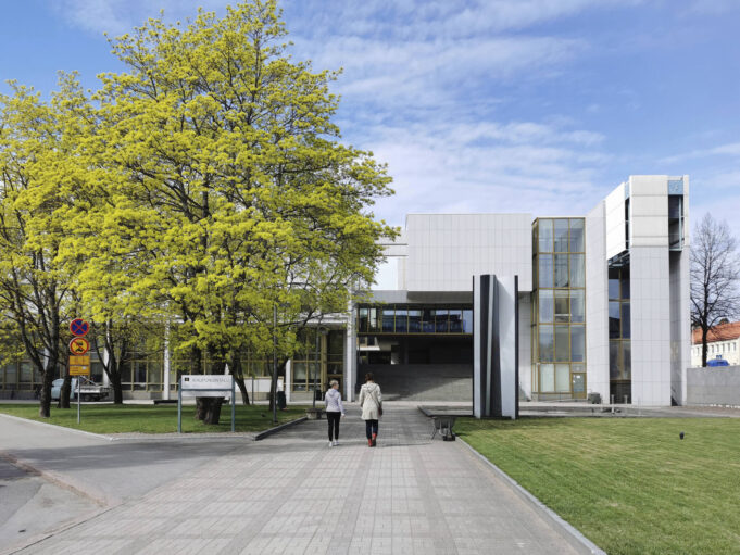 Light-coloured, large public building with a wide staircase leading up into the interior. Two people are walking toward the building. Kouvola City Hall.