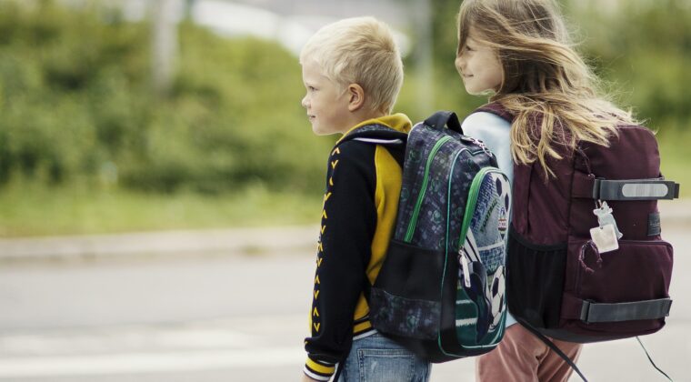 Kaksi lasta reput selässä suojatiellä