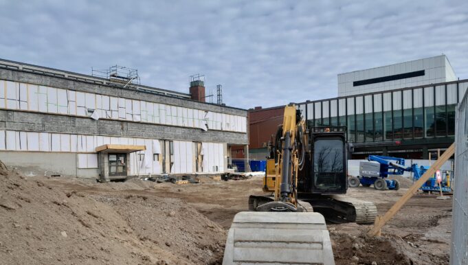 Kouvolan uuden teatterin rakennustyömaa. Edessä näkyy kauhakuormaaja ja hiekkaa, taustalla nykyinen teatteri sekä kuntotalo, jota saneeratan.
