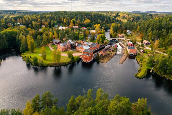 The Verla area from the air. Old red-brick factory buildings in a lush green lakeside landscape.