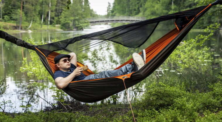 Mies makaa riippumatossa Käyrälammen ulkoilureitin varrella.