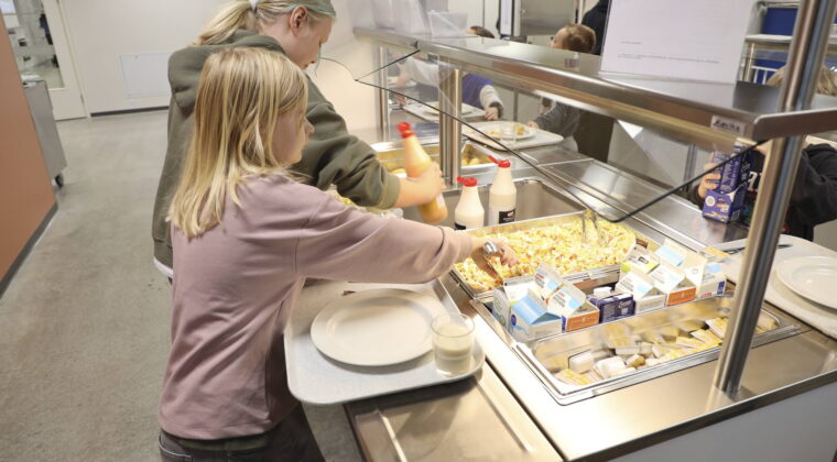 Kaksi oppilasta ottamassa ruokaa koulun ruokalinjastolta.